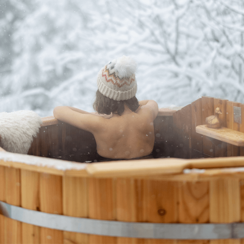 femme de dos dans un bain nordique sous la neige